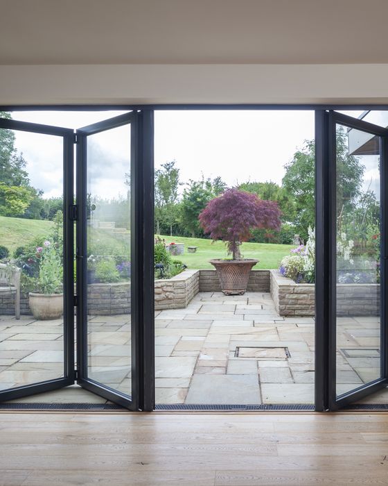 Black Visofold 1000 aluminium bi-fold doors folded open onto a patio
