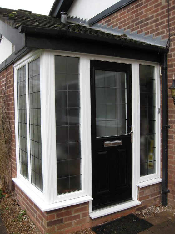 Black uPVC front door inside a white glazed porch